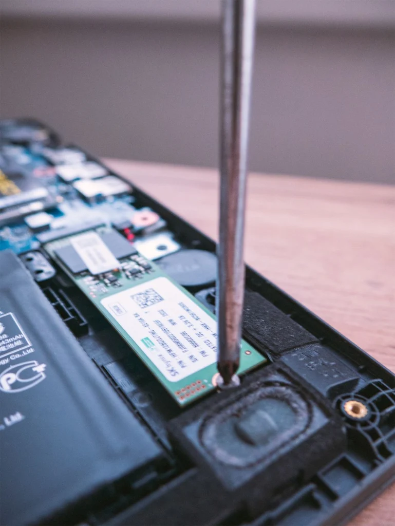 Šroubovák uvolňuje šroub disku M.2 SSD v otevřeném notebooku