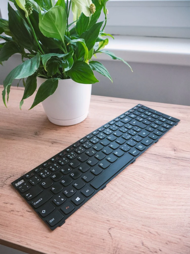 Vyjmutá klávesnice notebooku položená na stole před výměnou