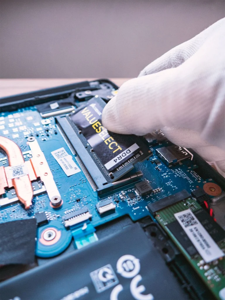 Ruka v ochranné rukavici zasouvá paměťový modul DDR4 do slotu v notebooku